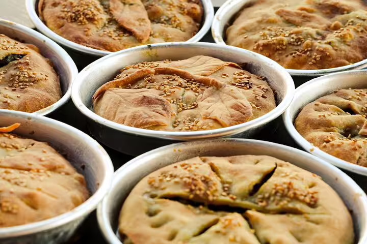 Freshly baked Greek pies in round tins at Athens cooking class, homemade pastries for rooftop dinner experience