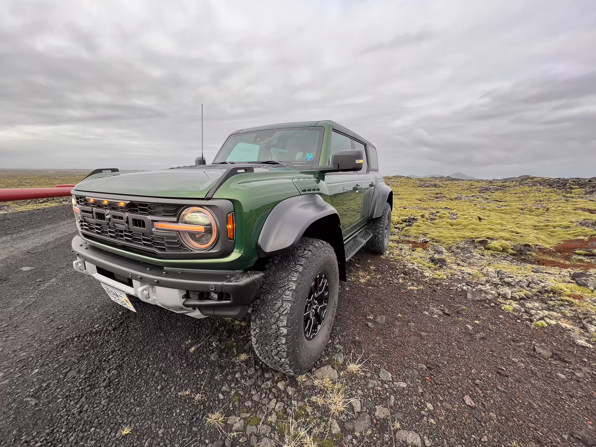 Green Ford Bronco Raptor 4x4 parked on volcanic landscape with moss-covered lava fields in Iceland