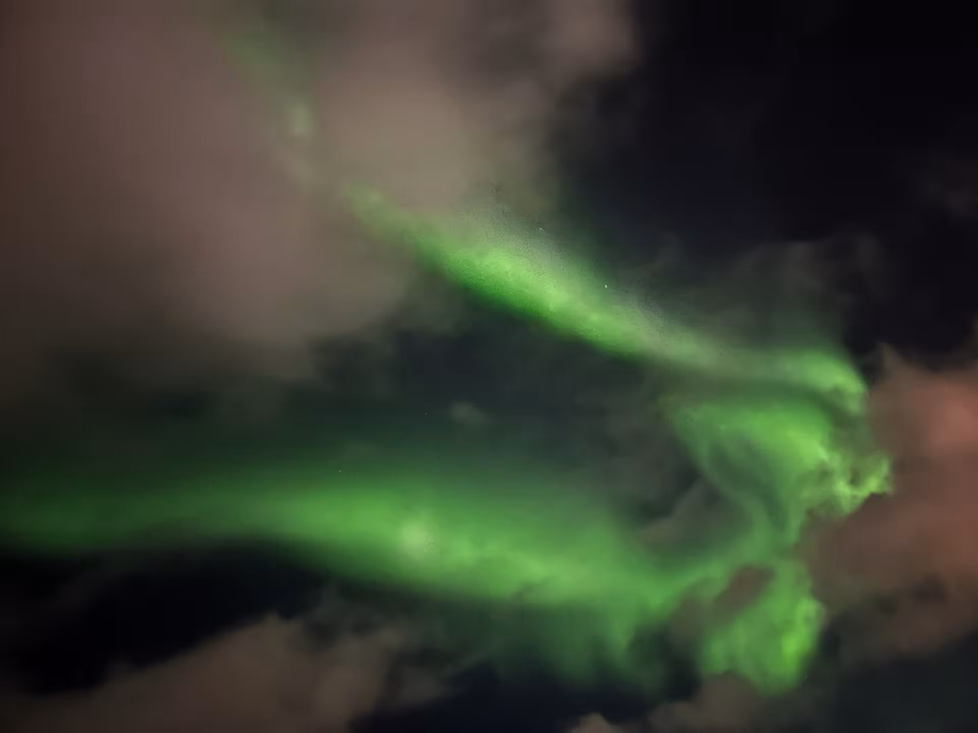 Green aurora waves shining over the Icelandic sea at night