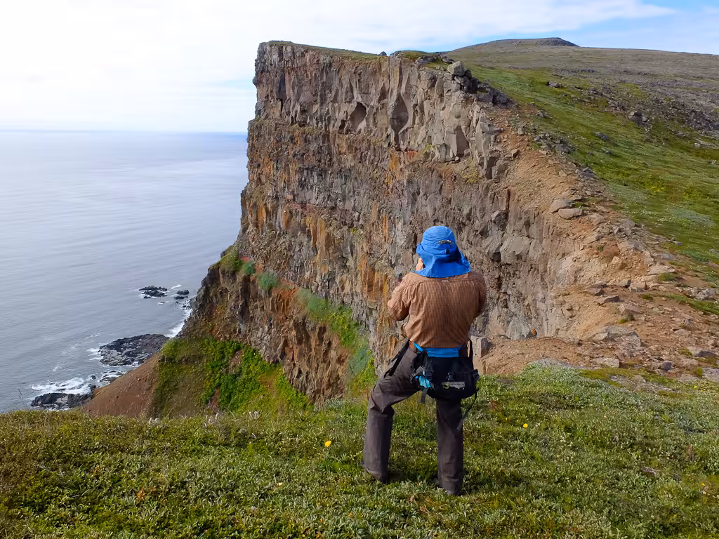 Hiker overlooking towering sea cliffs in Iceland’s Hornstrandir Nature Reserve on the Green Cliffs tour