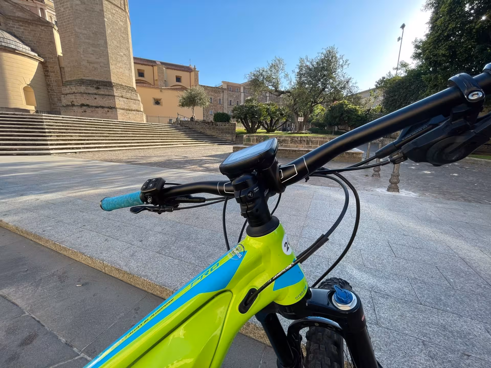 Close-up of green e-bike handlebars with scenic Sardinian backdrop, ideal for touring Oristano's historic sites.