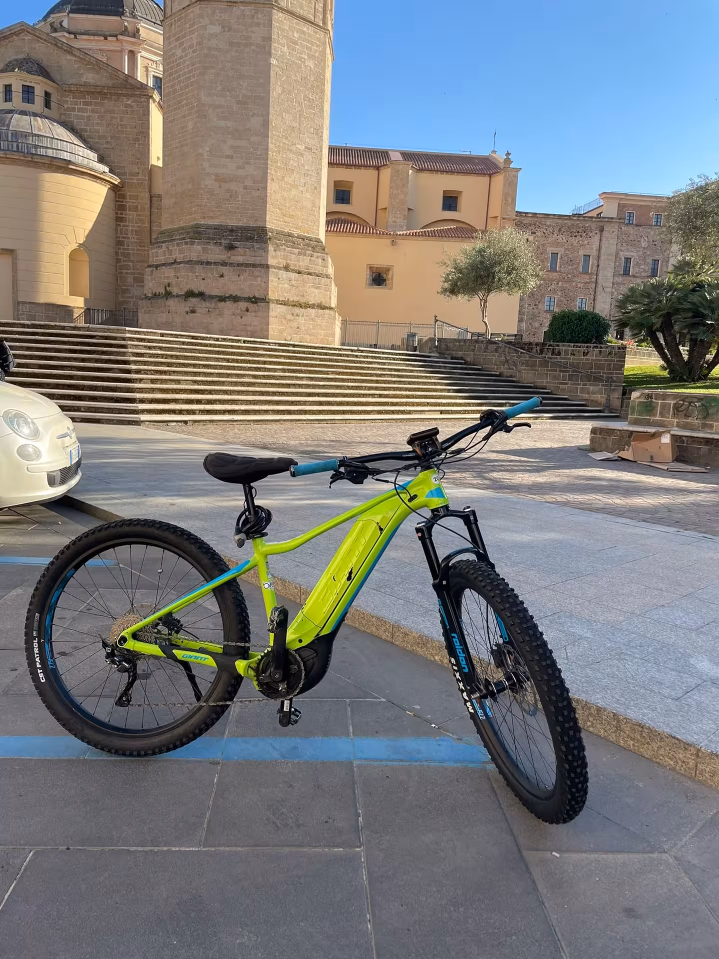 Vibrant green e-bike set against Oristano's historic buildings, offering an eco-friendly way to explore Sardinia.