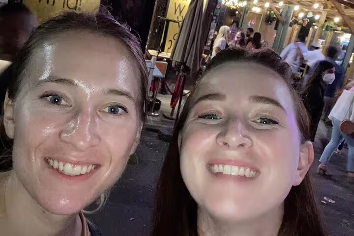 Two smiling women on a lively Greenwich Village street at night