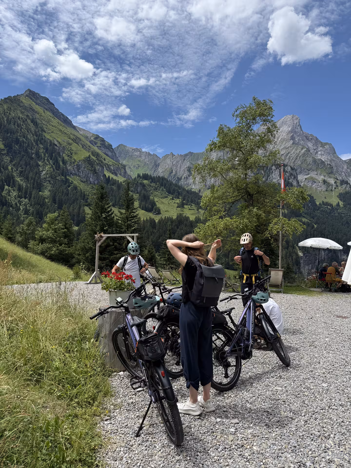 Group of E-bike cyclists taking a break with panoramic Swiss Alps peaks in Griesalp UNESCO alpine valley