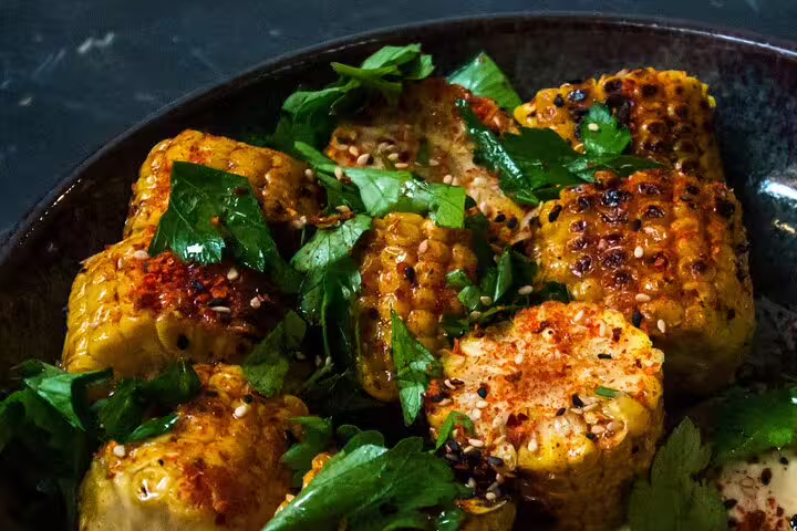 Grilled corn with fresh herbs and spices, ideal for organic wine tasting and gourmet food pairing experiences.