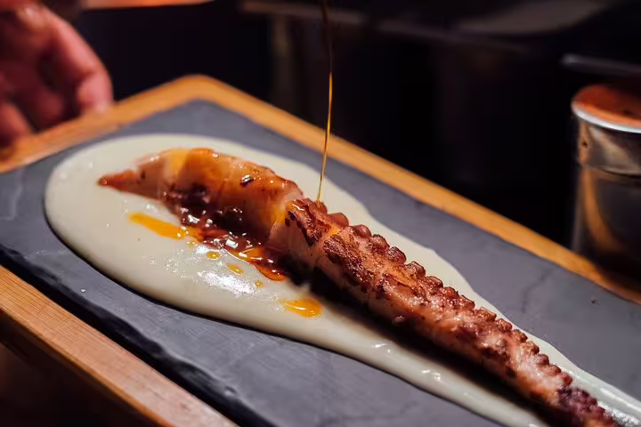 Grilled octopus with sauce on slate at a private tapas and wine walking tour in Barcelona.
