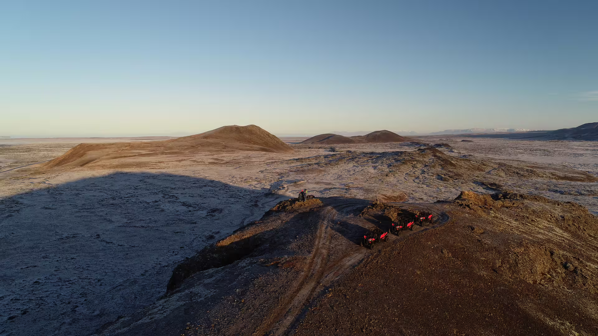 Buggy tour group parked on volcanic lava ridge near Grindavik with snow-dusted craters in background