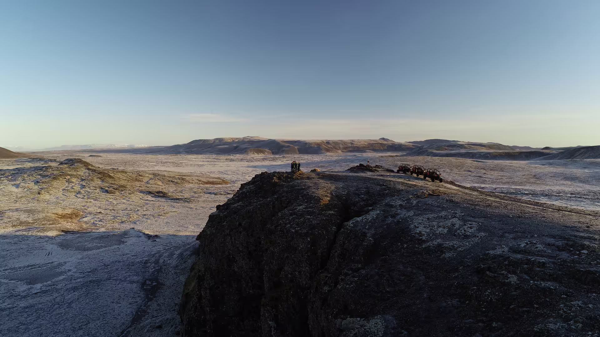 Buggy vehicles parked on volcanic lava rock outcrop overlooking vast lava fields near Grindavik, Iceland
