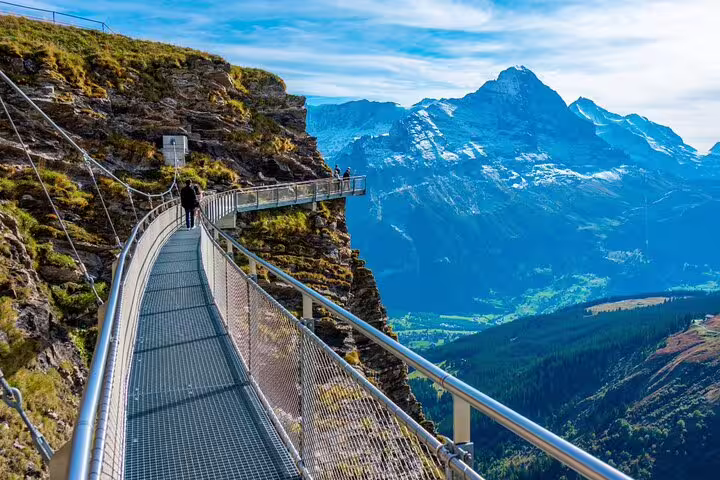 Scenic walkway along a cliff with stunning views of the Swiss Alps, part of the Grindelwald First adventure tour.