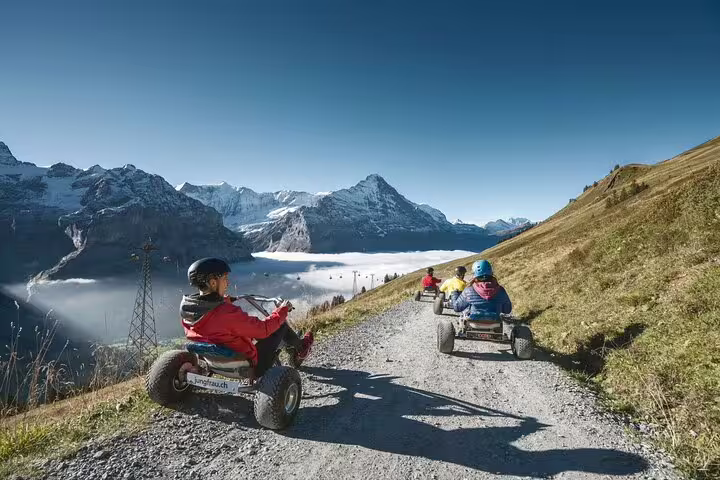 Adventure seekers ride mountain carts on a scenic trail with breathtaking views of the Swiss Alps in Grindelwald.
