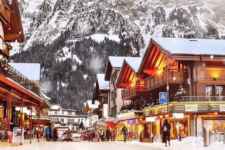 Charming winter scene in Grindelwald with snow-covered streets, cozy lights, and majestic mountain backdrop.