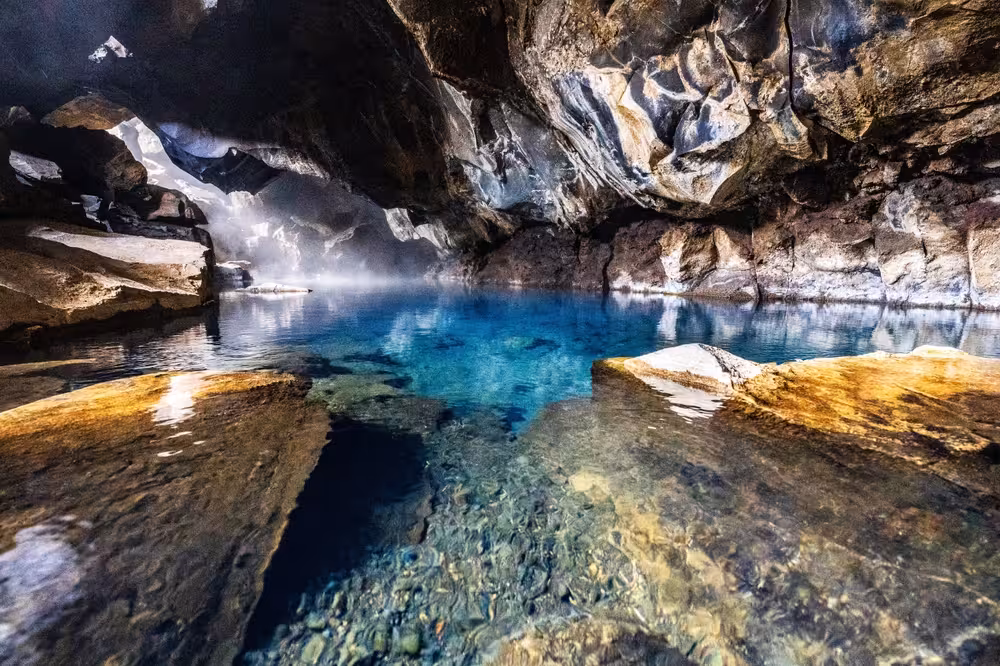 Crystal clear geothermal cave pool with turquoise water and misty steam near Lake Myvatn, Iceland