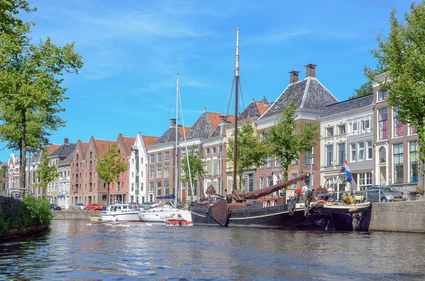 Sailboats on Groningen canal beside historic houses, scenic view on the 1-day walking tour with audioguide in 7 languages