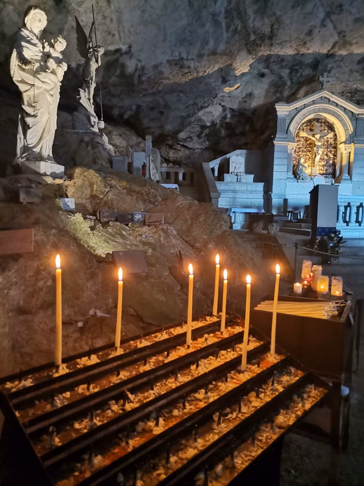 Candles and Virgin Mary statue by the altar inside Grotte Sainte-Madeleine, a sacred hike pilgrimage cave