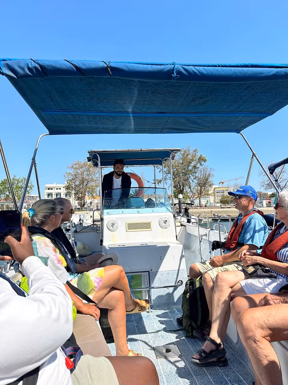 Guests wearing life jackets on a shaded boat, enjoying a small-group cruise tour with local skipper and calm waters
