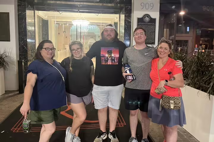 Group of five friends posing outside 909 building entrance at night in Houston