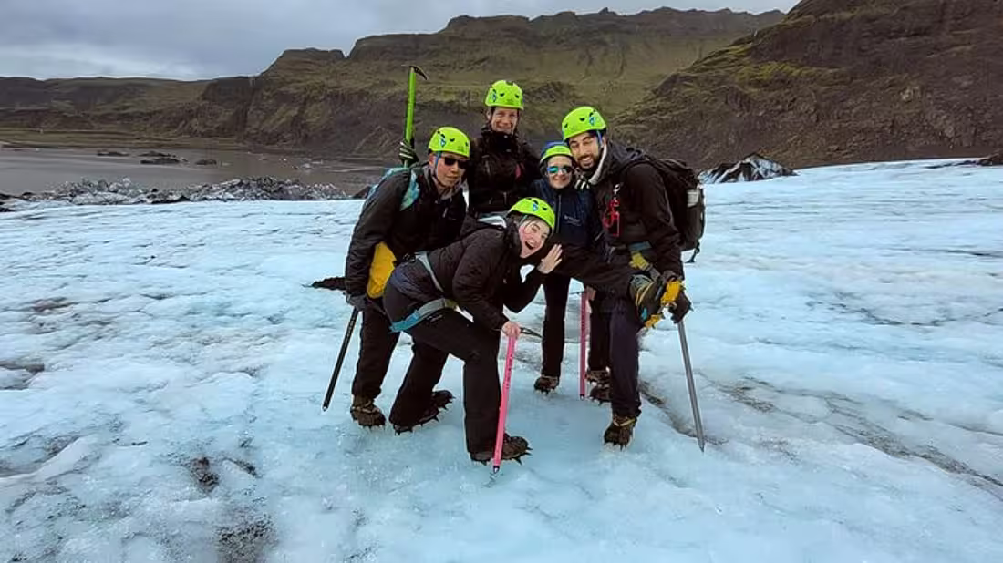 A group on tour in hiking gear posing for a photo on a glacier