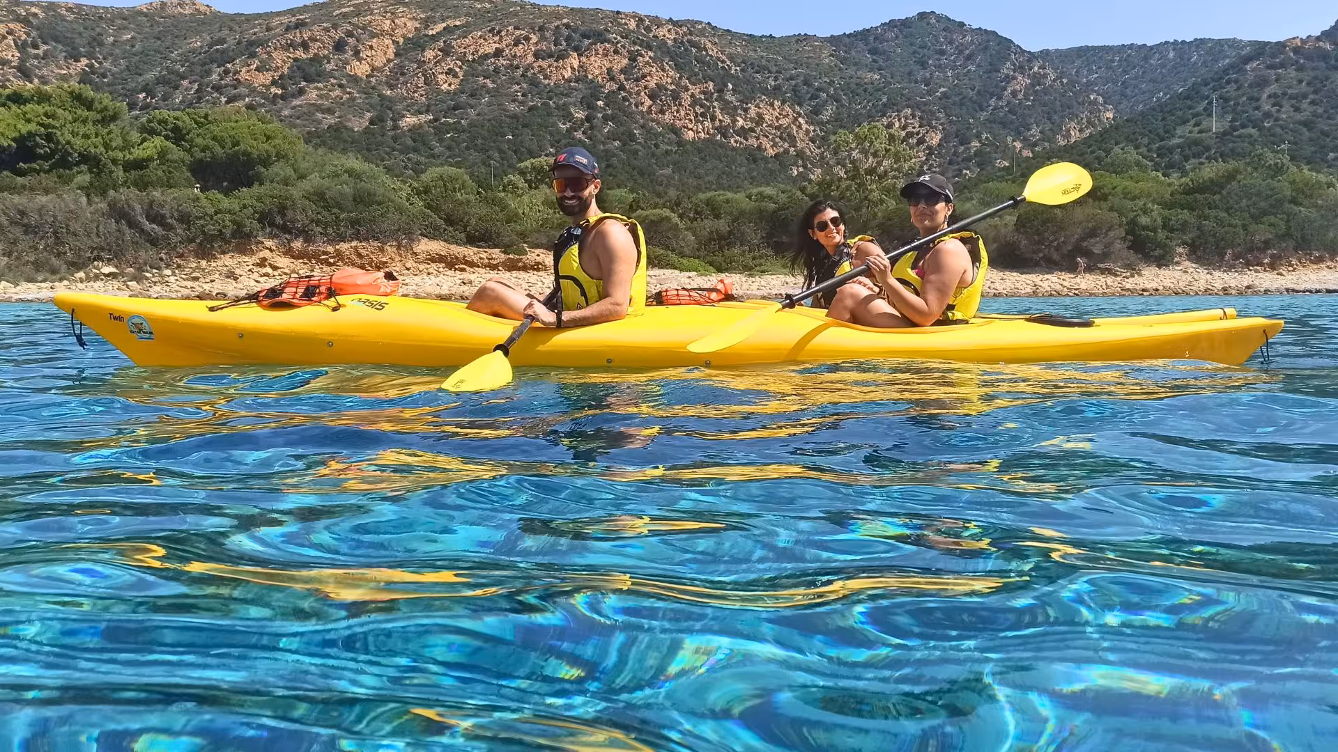 Group kayaking in vibrant blue waters near Tuerredda, surrounded by scenic Sardinian landscapes.