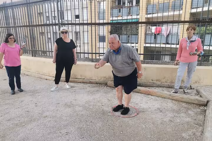 Group playing petanque in Marseille on a gravel court, friendly guided lesson with boules in Provence