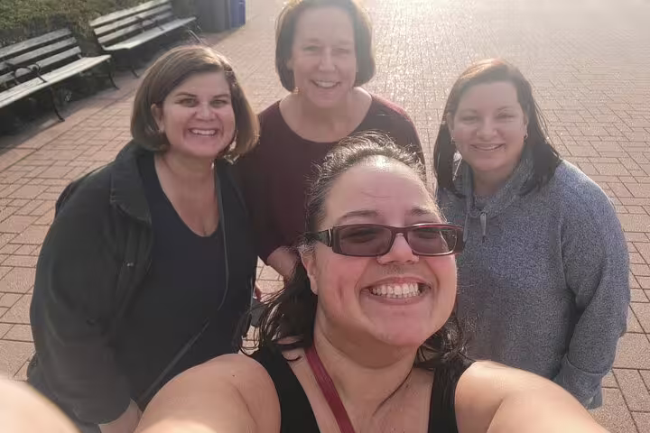 Four smiling women taking a group selfie outdoors on a brick plaza in Grant Park Chicago