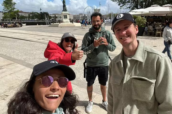 Four happy tourists taking a selfie at La Rochelle Old Port waterfront square on a sunny day