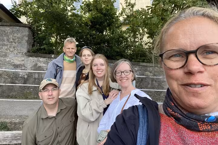Group of six tourists smiling for a selfie on stone steps in Salzburg Old Town