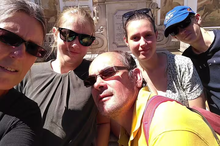 Group of five tourists taking a selfie in front of a Salzburg fountain on a sunny day