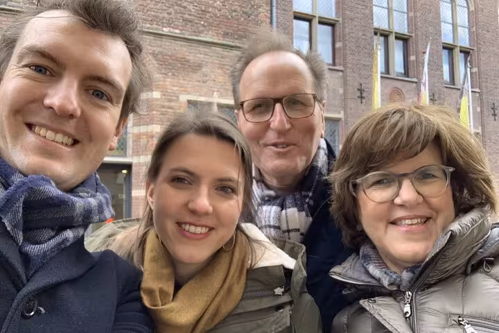 Four smiling tourists taking a selfie in front of a historic brick building in Utrecht