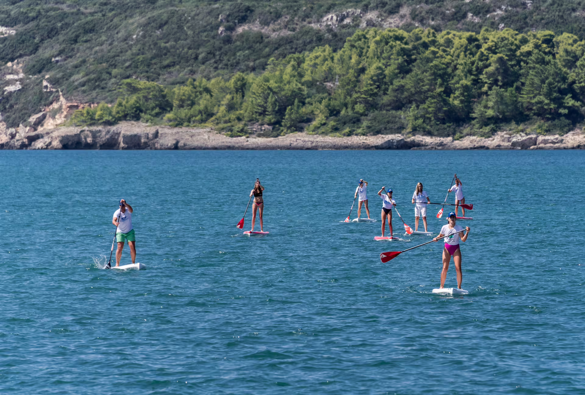 Group stand up paddleboarding on the clear sea near Kardamyli, Mani coast, guided SUP tour in Greece