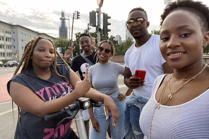 Group of five smiling friends posing together on a street in Frankfurt city center