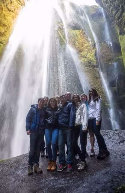 Group of tourists posing in front of a massive waterfall on Iceland's South Coast