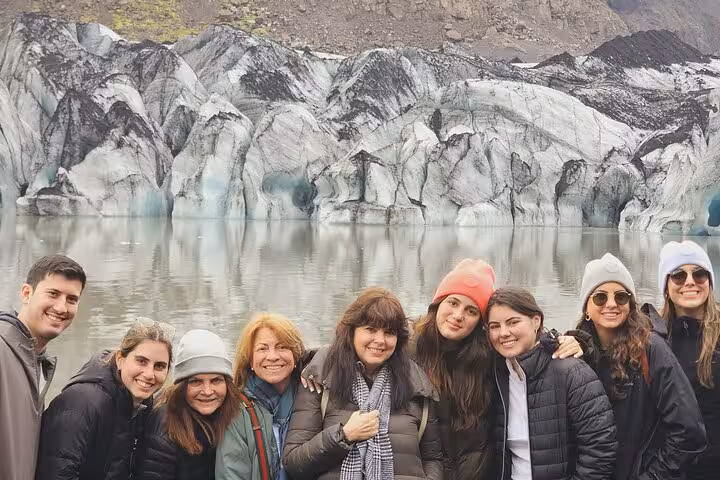 Group of tourists posing in front of a glacier and glacial lagoon on Iceland's South Coast