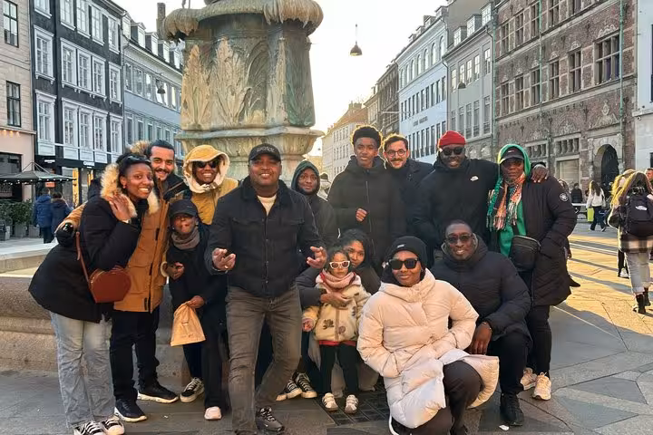 Group of tourists posing by a fountain in Copenhagen city center on a walking tour