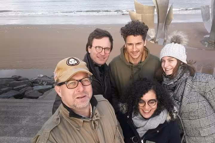 Group of five tourists taking a selfie at Normandy D-Day beach on a cloudy day