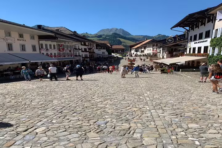 Charming cobblestone street in Gruyères village bustling with tourists, perfect for exploring Swiss culture.