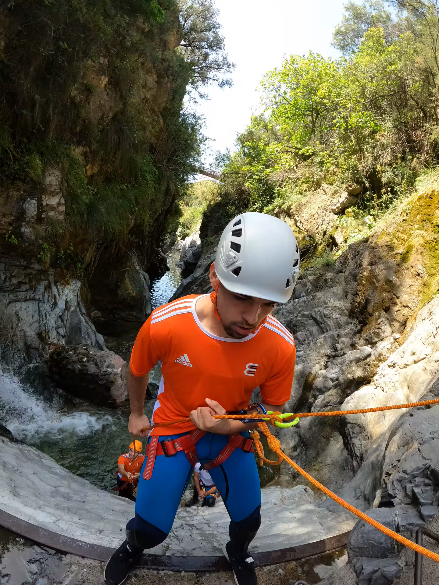 A guide in safety harness carefully descends a steep canyon wall on the thrilling Guadalmina canyoning tour in Estepona