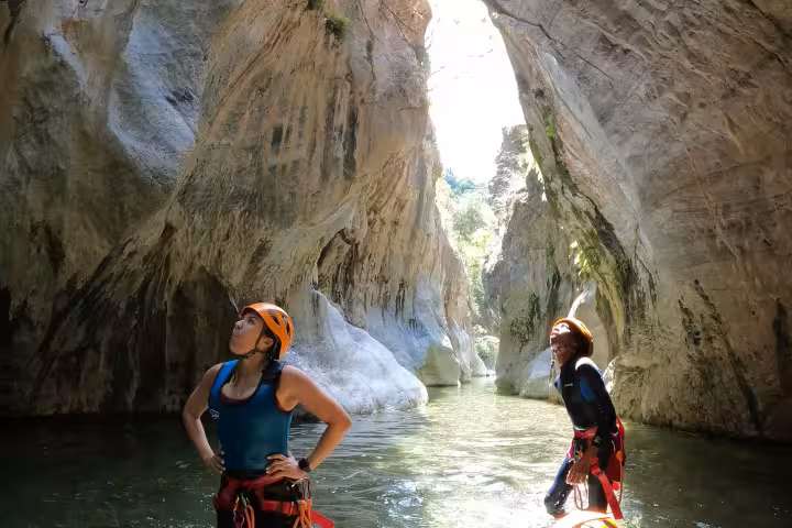 Two helmeted canyoners marveling at towering narrow gorge walls in Guadalmina Canyon guided tour Estepona