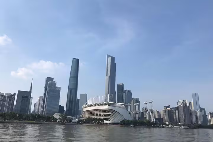 Guangzhou skyline featuring iconic high-rise buildings along the Pearl River under a clear blue sky, perfect for sightseeing.