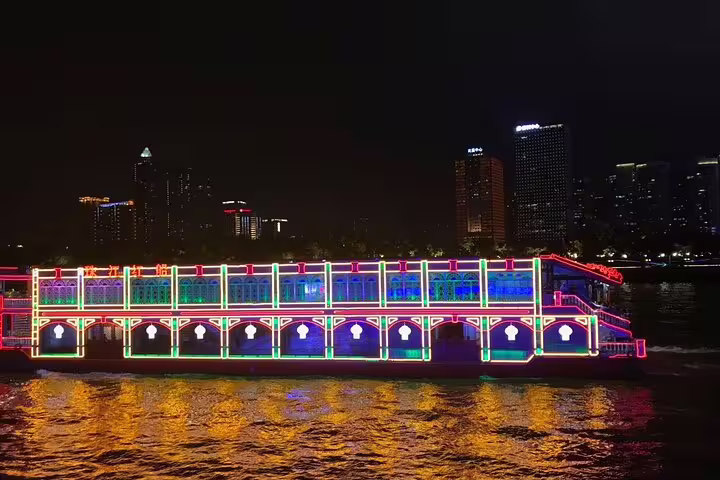 Vibrant neon-lit boat cruising on the Pearl River in Guangzhou, offering a lively night tour with stunning city views.