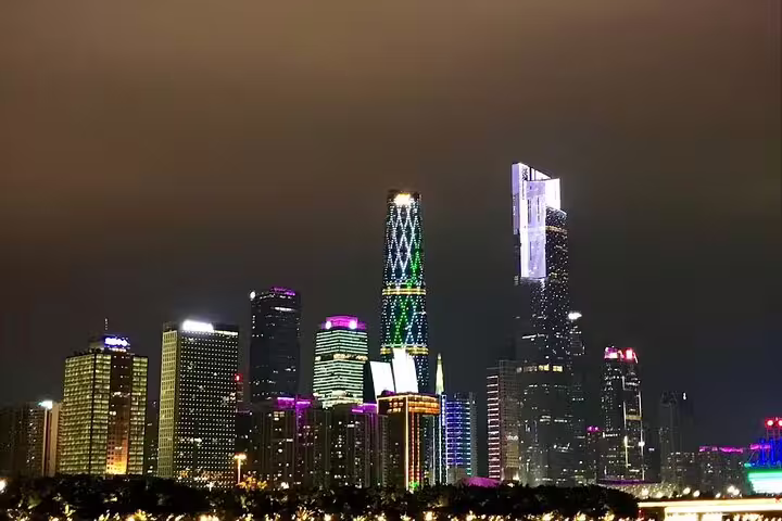 Illuminated Guangzhou skyscrapers at night, reflecting vibrant city lights along the Pearl River.