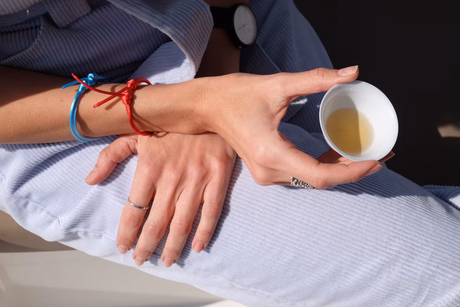 Close-up of guest holding a small cup of green tea during a mindful tea ceremony tasting session