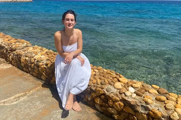 Guest sitting on a stone seawall at Ain El Sokhna, clear Red Sea water on a day tour from Cairo