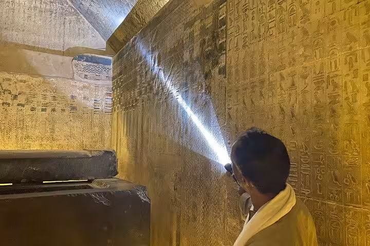 Guide shines flashlight on hieroglyphs inside Saqqara tomb on private Giza Pyramids, Memphis tour