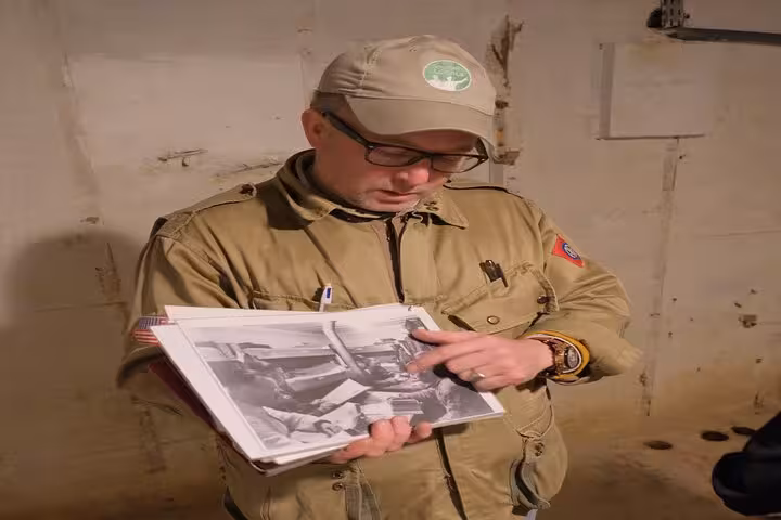 Tour guide examining black and white WWII photos during D-Day Normandy tour