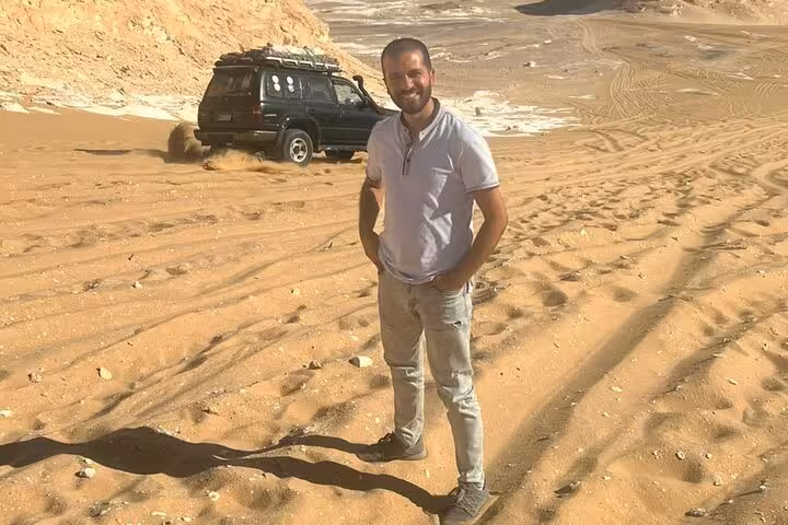Guide on sand dunes beside 4x4 in Egypt desert, part of 3-day White Desert Black Desert and Djara Cave safari