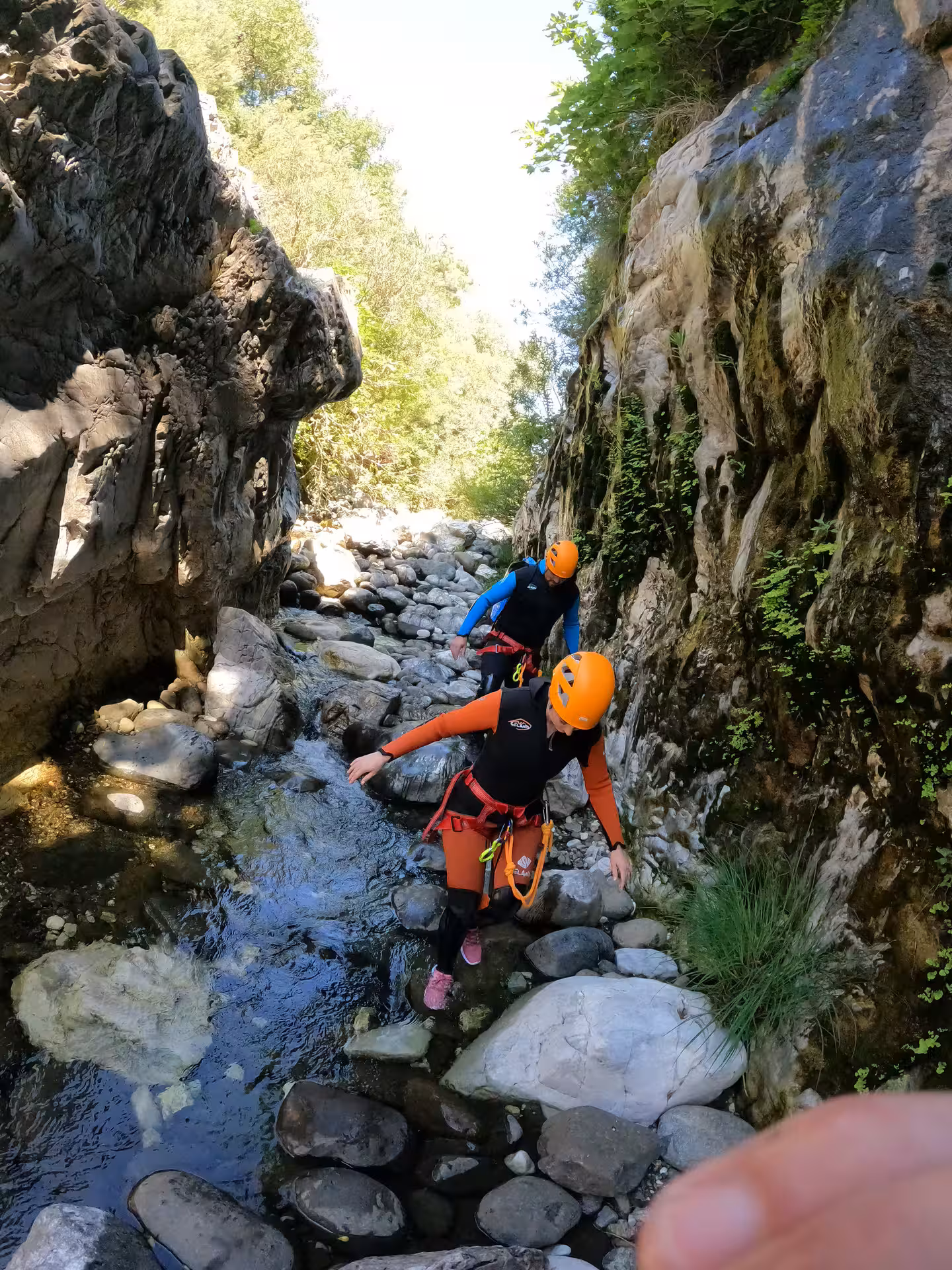 Two canyoners in helmets and harnesses navigating rocky stream on guided canyoning adventure in Guadalmina Canyon Estepona