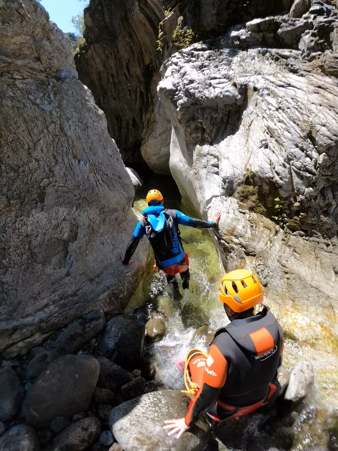Guide and participant in wetsuits navigating a rocky stream passage on a guided canyoning tour in Guadalmina Canyon near Estepona
