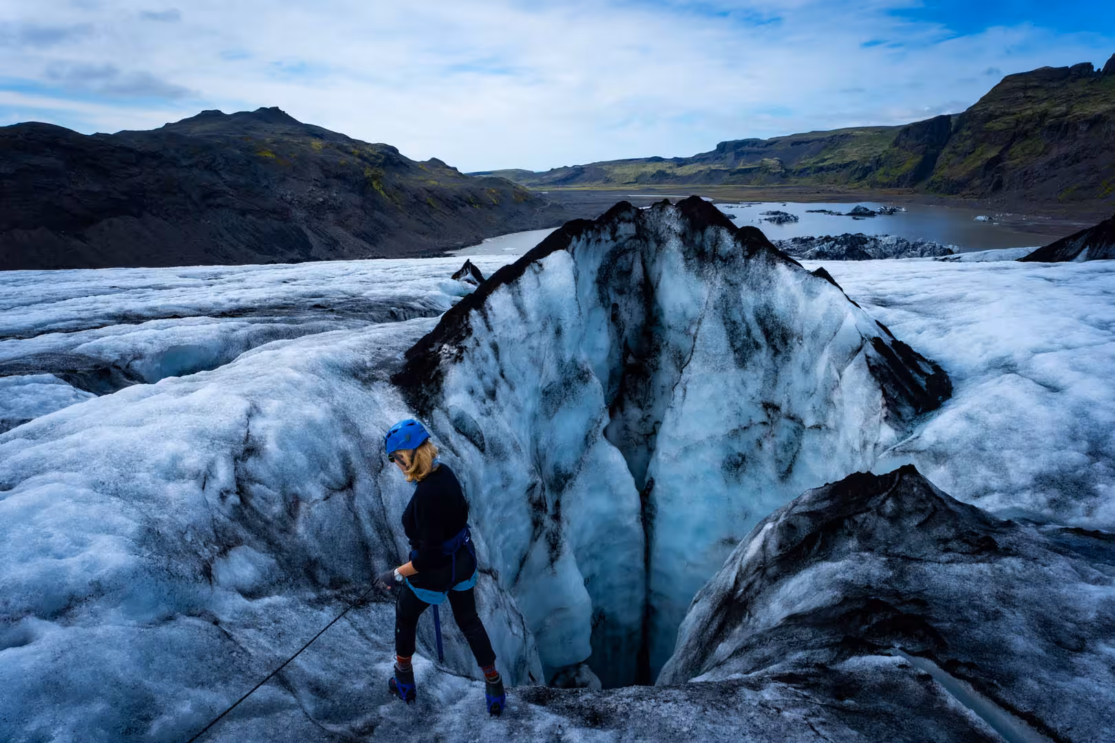 Climber with blue helmet and rope navigating a glacial crevasse on Solheimajokull glacier, Iceland
