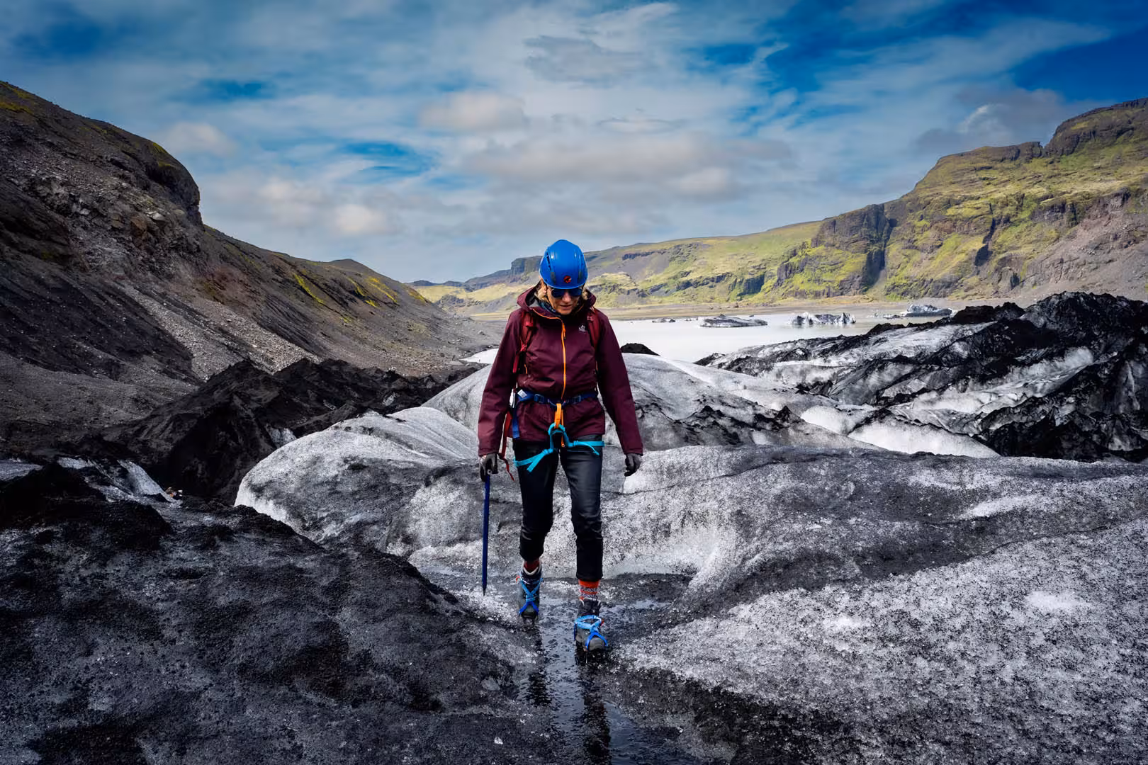 Female hiker with blue helmet and ice axe walking on Solheimajokull glacier in Iceland