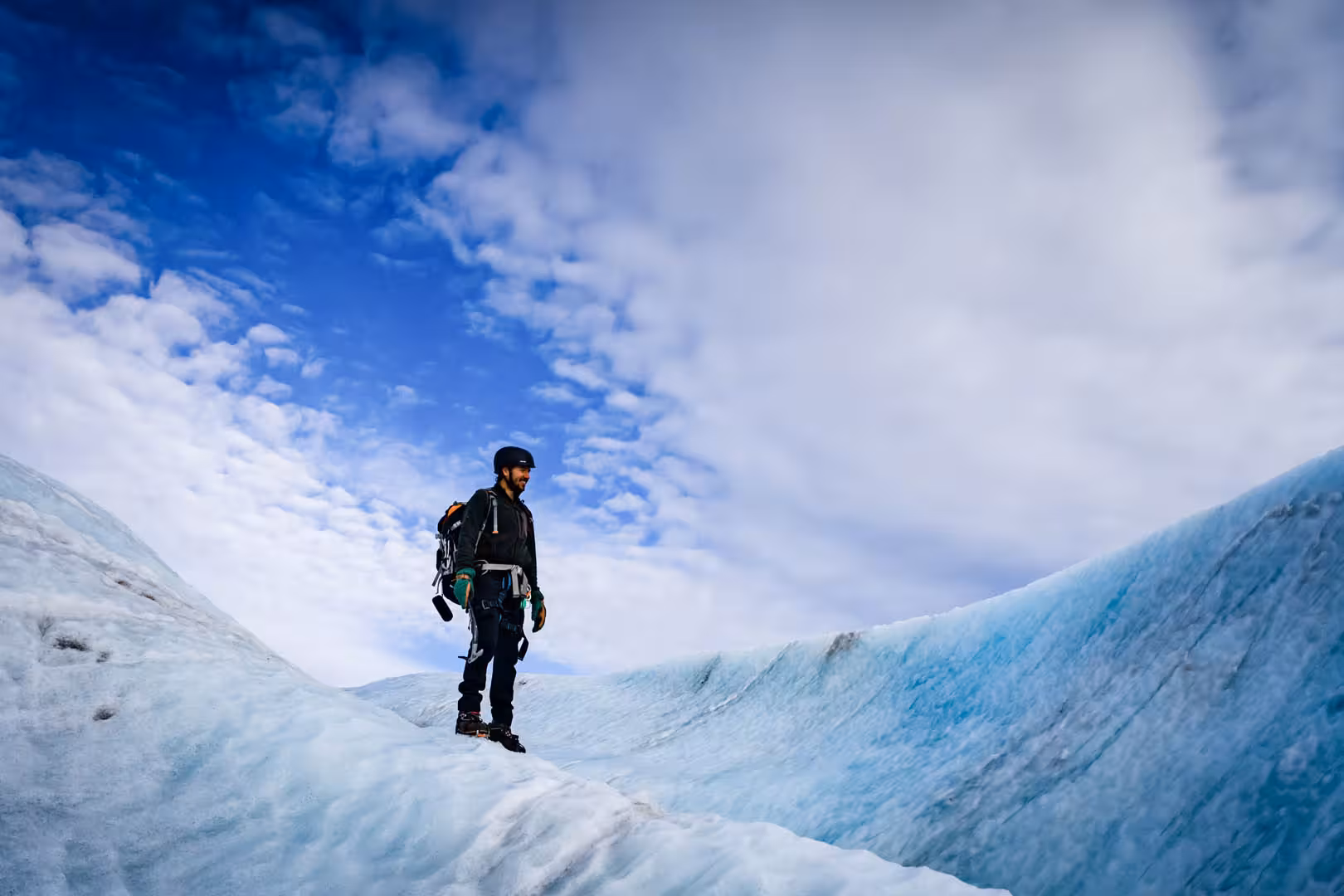 Guide standing on blue glacial ice at Solheimajokull glacier in Iceland wearing climbing gear